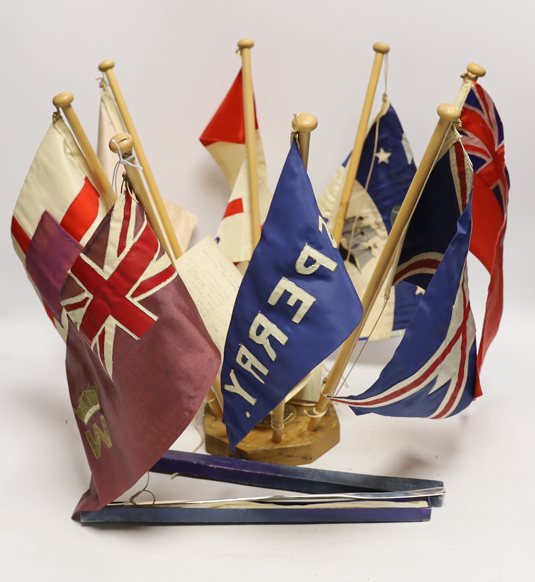 Collection of mid 20th century merchant shipping pennants on a stand and a boxed George V silver model of an oar, inscribed ‘Second Destroyer Flotilla Regatta 1934’